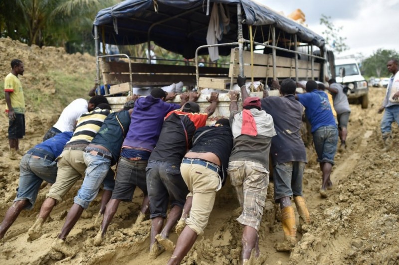 People try to dislodge a truck stuck in the mud in Papa New Guinea